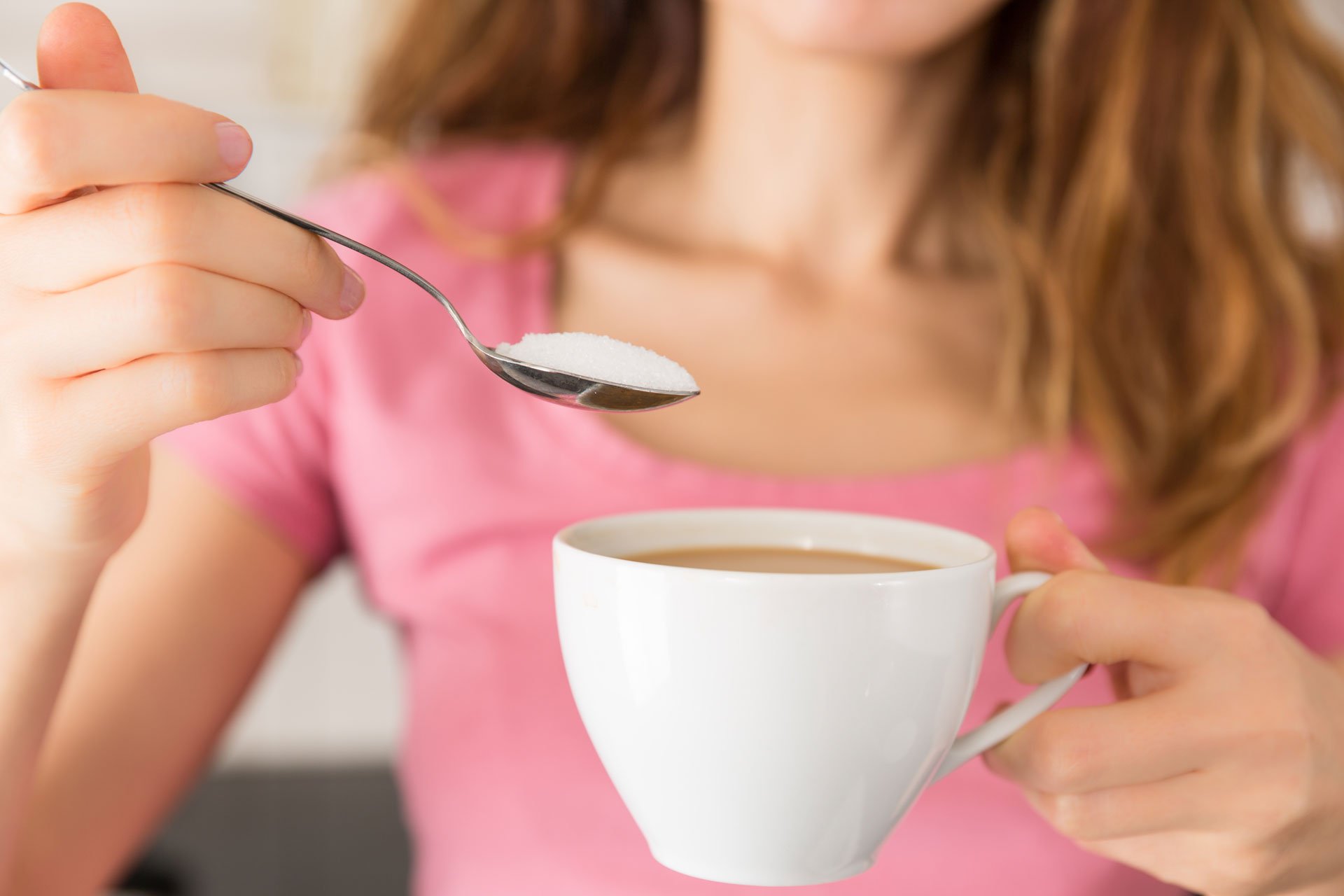 woman using a sugar substitute in her coffee