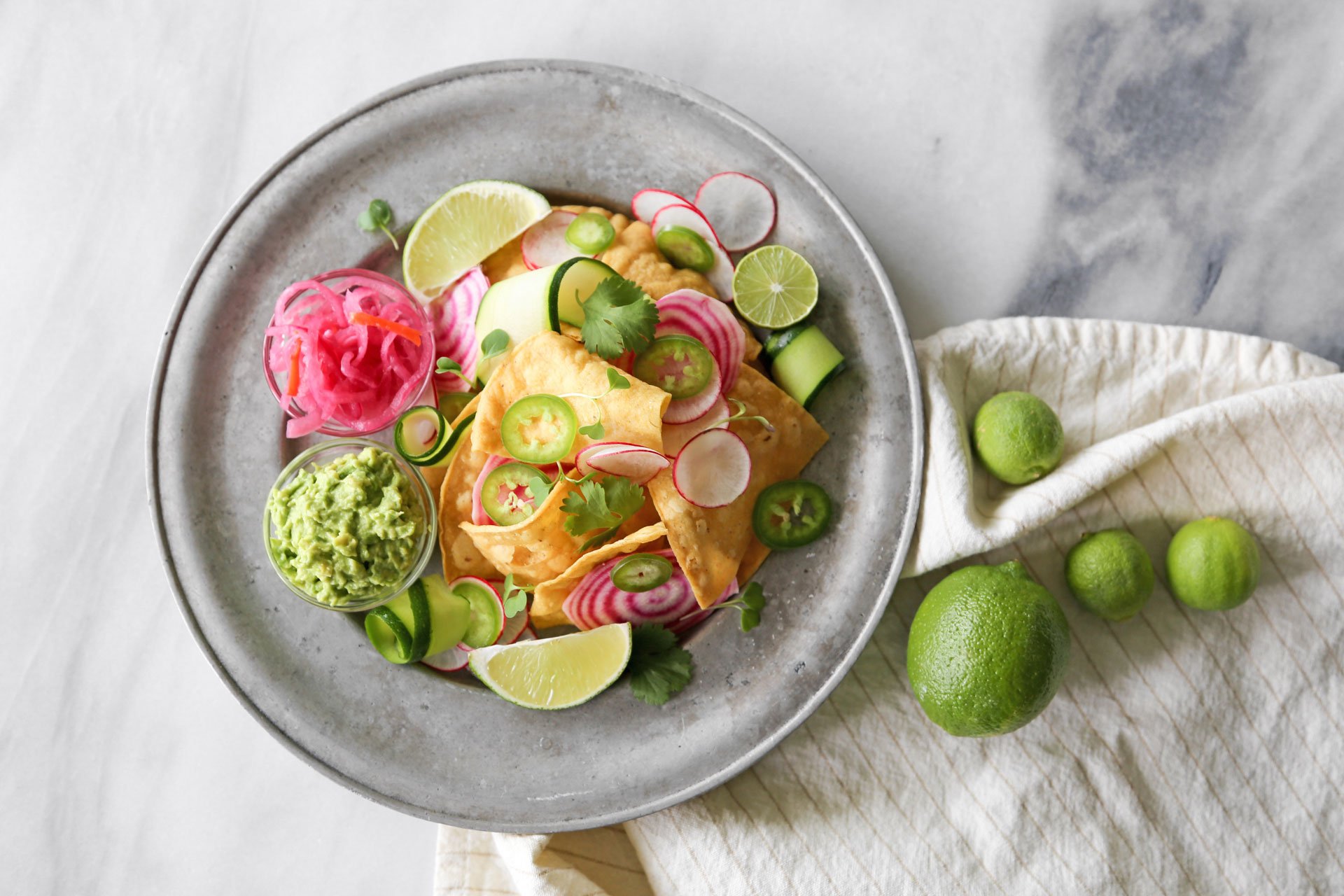 Chips and guacamole with pickled onion, limes, and radishes