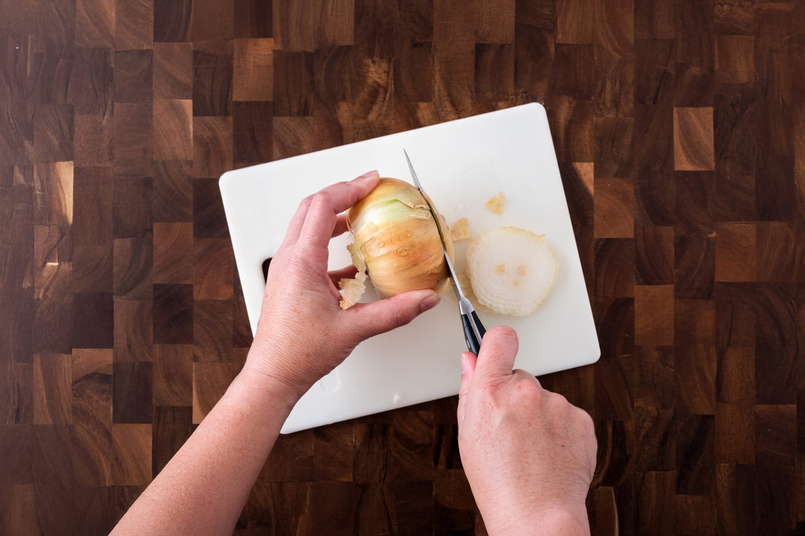 cutting an onion on a plastic cutting board