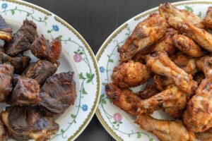 a plate of grilled beef next to a plate of chicken pieces