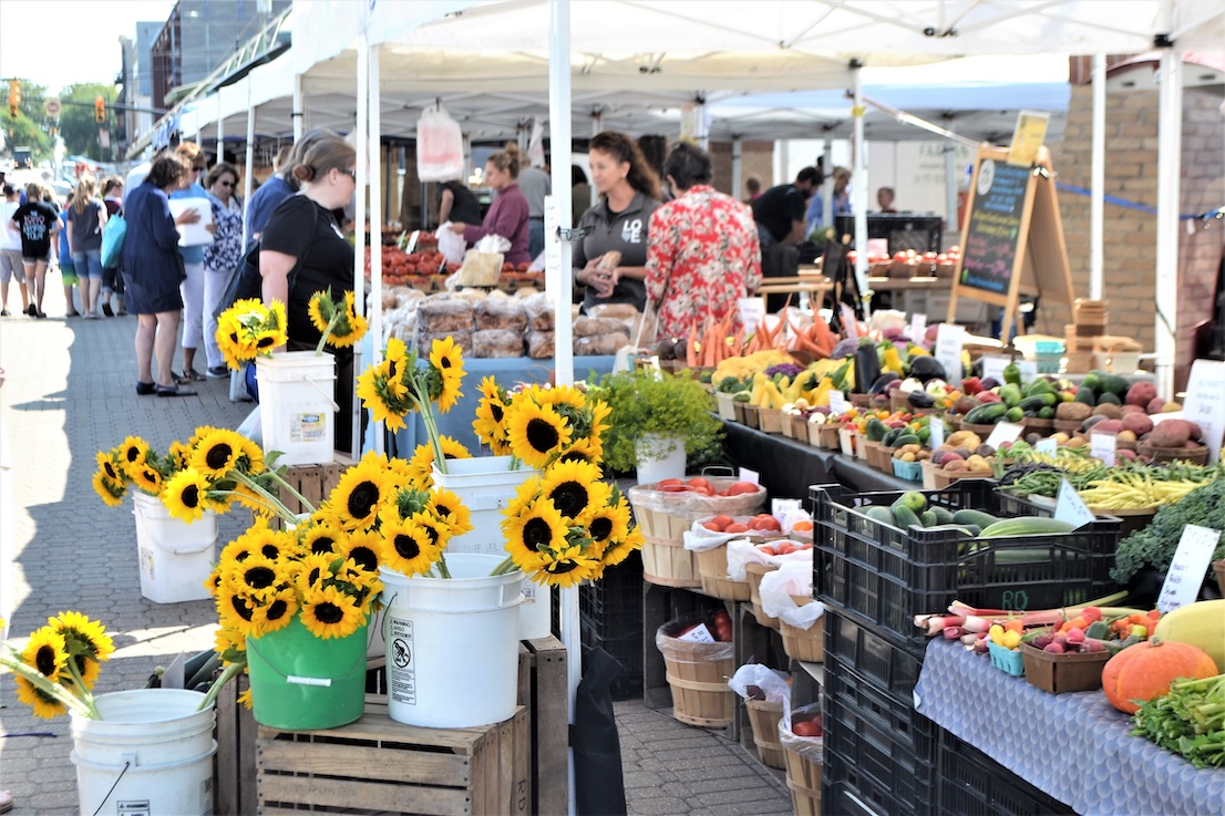 sunflowers and assorted vegetables at a farmers market stand